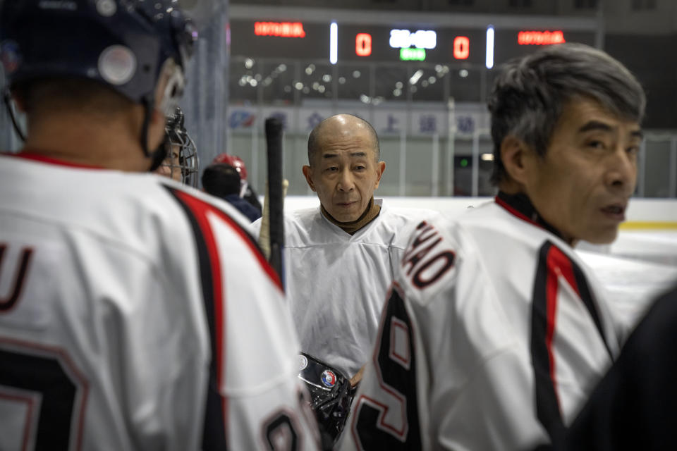 Members of the "1979" hockey club gather on the bench before a match at a hockey rink in Beijing, Wednesday, Jan. 12, 2022. Spurred by enthusiasm after China was awarded the 2022 Winter Olympics, the members of a 1970s-era youth hockey team, now around 60 years old, have reunited decades later to once again take to the ice. (AP Photo/Mark Schiefelbein)