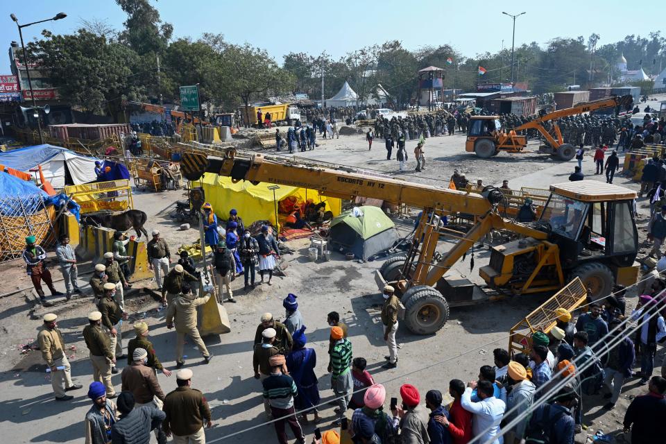 Farmers (R) watch as police (C) set up road blocks at the Delhi-Haryana state border in Singhu on January 27, 2021, as farmers continue to demonstrate against the central government's recent agricultural reforms. (Photo by Money SHARMA / AFP) / The erroneous mention[s] appearing in the metadata of this photo by Money SHARMA has been modified in AFP systems in the following manner: [at the Delhi-Haryana state border in Singhu] instead of [at Singhu border in New Delhi]. Please immediately remove the erroneous mention[s] from all your online services and delete it (them) from your servers. If you have been authorized by AFP to distribute it (them) to third parties, please ensure that the same actions are carried out by them. Failure to promptly comply with these instructions will entail liability on your part for any continued or post notification usage. Therefore we thank you very much for all your attention and prompt action. We are sorry for the inconvenience this notification may cause and remain at your disposal for any further information you may require. (Photo by MONEY SHARMA/AFP via Getty Images)