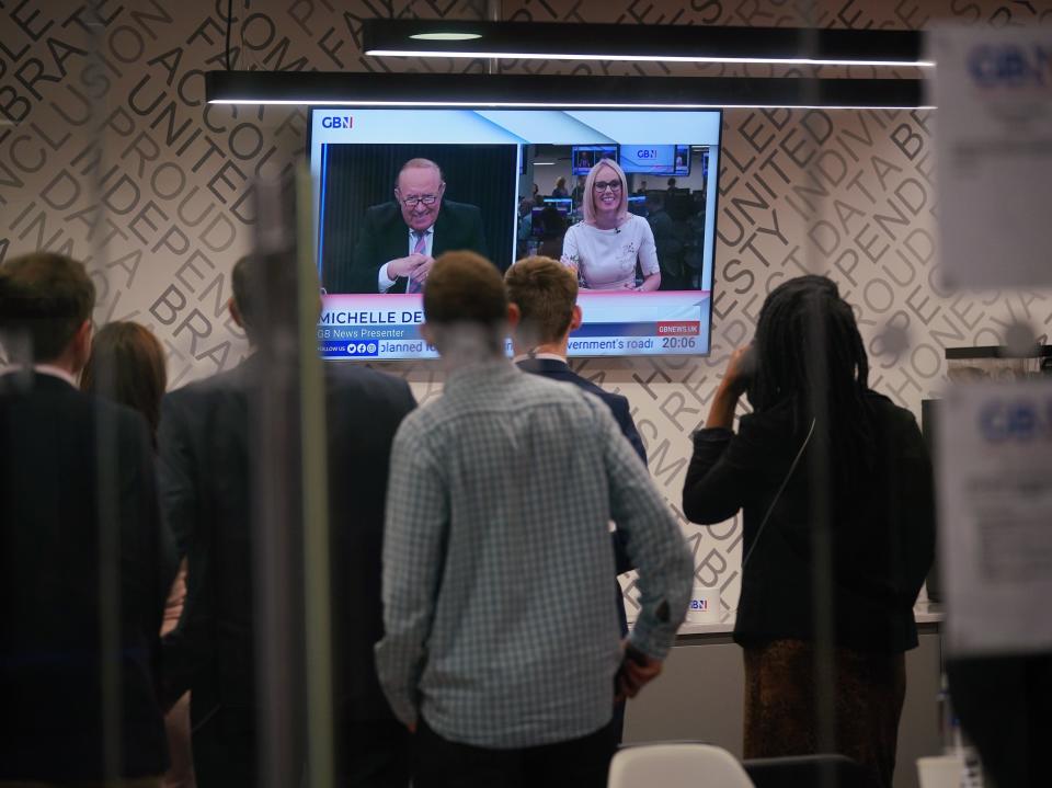 Staff in the green room watching a television screen showing presenters Andrew Neil and Michelle Dewberry broadcast from a studio, during the launch event for new TV channel GB News (Yui Mok/PA)