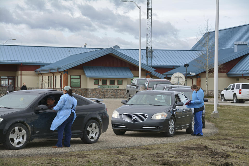 In this Thursday, April 29, 2021, photo, nurses interview patients through their car windows after providing them with COVID-19 vaccines at the Piegan-Carway border crossing after they drove from Canada to Montana to receive excess doses from the Blackfeet tribe, near Babb, Mont. (AP Photo/Iris Samuels)