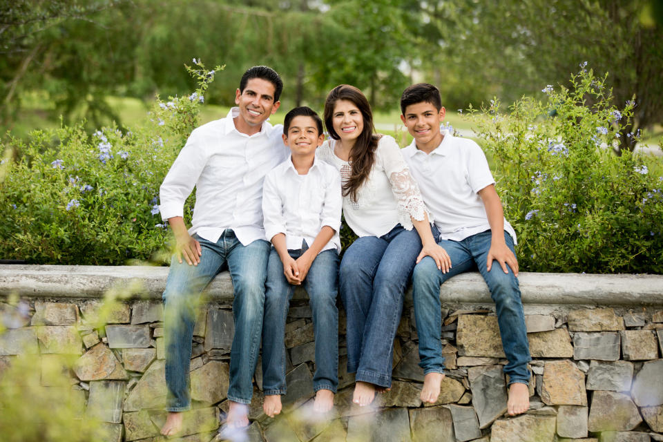 A photo of a family mom, dad, and two sons all wearing blue jeans and white shirts