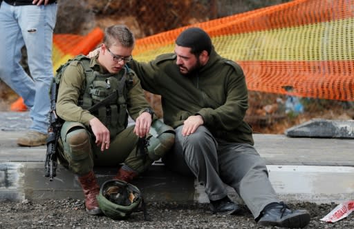 An Israeli soldier is consoled at the site of a drive-by shooting at a West Bank bus stop on December 13, 2018