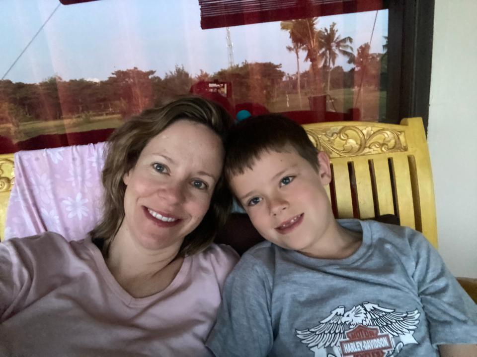 Melissa Noble sitting with her son on a bench and smiling.