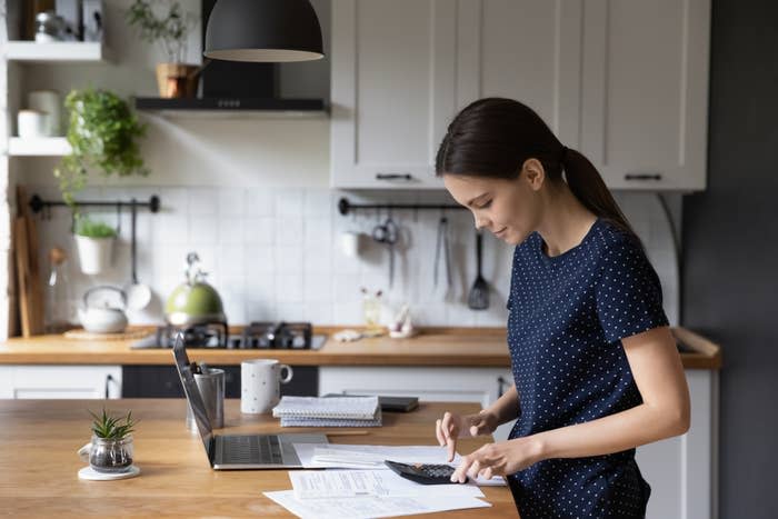 young woman calculating personal expenses at kitchen counter