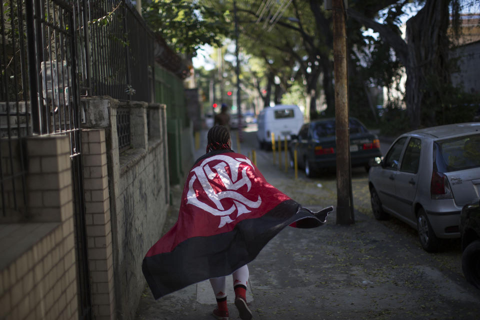 In this May 4, 2014 photo, Maria Boreth de Souza, alias Zica, drapes herself in a Flamengo soccer team flag as she walks to Maracana stadium to watch her team play in Rio de Janeiro, Brazil. The 63-year-old Souza, who is one of the most die-hard and the best known fans of the iconic team, has over the years become an icon in her own right. (AP Photo/Leo Correa)