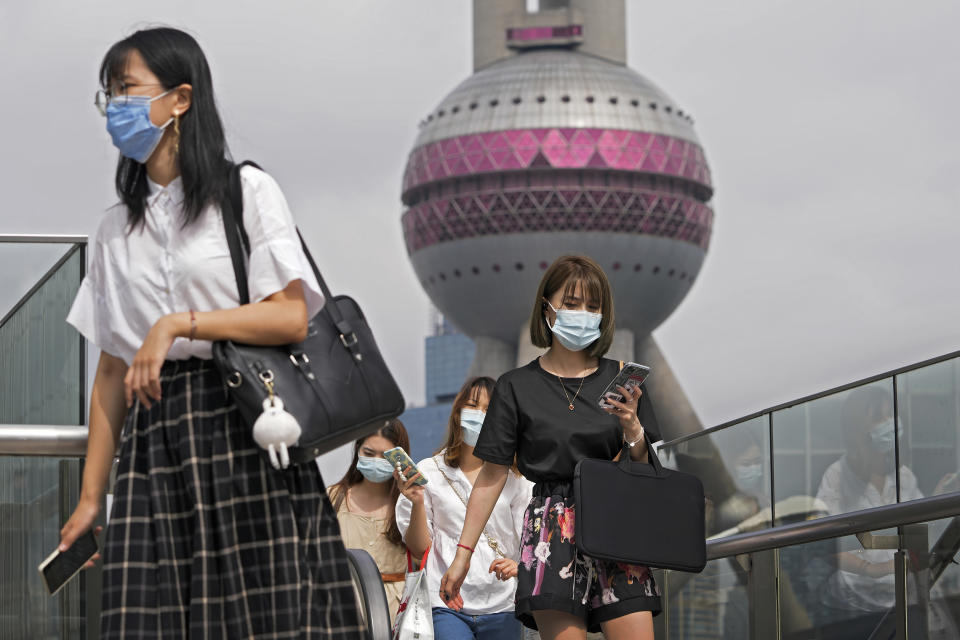 Women wearing face masks to help curb the spread of the coronavirus walk on a pedestrian overhead bridge in front of the Oriental Pearl TV Tower at the Pudong Financial District in Shanghai, China, Wednesday, Aug. 25, 2021. (AP Photo/Andy Wong)