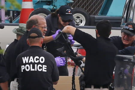 A police officer photographs a weapon removed from a truck in the parking lot of the Twin Peaks restaurant, where nine members of a motorcycle gang were shot and killed, in Waco, Texas May 19, 2015. REUTERS/Mike Stone