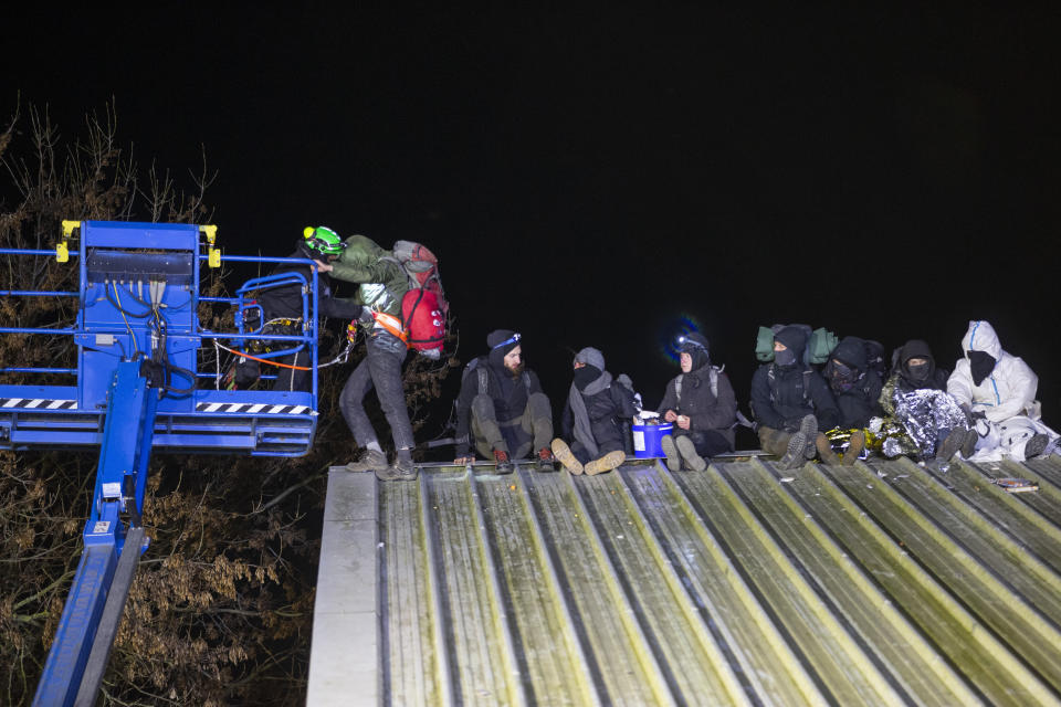 Climate activists sit on a barn roof and are brought down by height climbers of the police, in Luetzerath, Germany, Wednesday, Jan. 11, 2023. Police in riot gear began evicting climate activists Wednesday from the condemned village in western Germany that is due to be demolished for the expansion of a coal mine. Environmentalists say bulldozing the village to expand the nearby Garzweiler coal mine would result in huge amounts of greenhouse gas emissions. (Thomas Banneyer/dpa via AP)