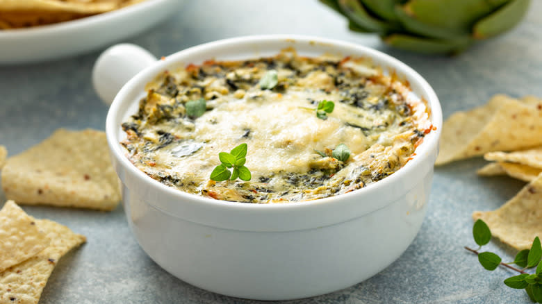 Ramekin of spinach and artichoke dip with tortilla chips