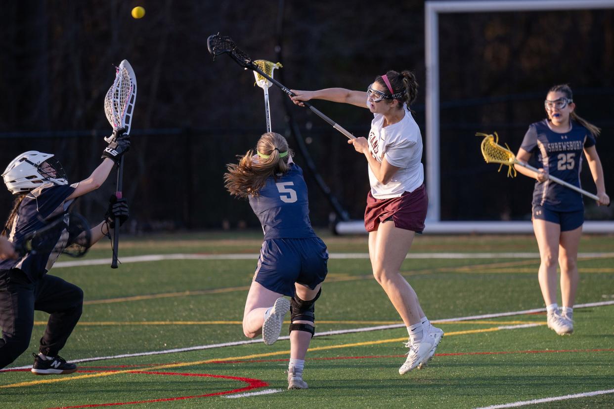 Algonquin's Bella Roman fires a shot past Shrewsbury's Tierney Daly and goalkeeper Sophie Wilson during a girls' lacrosse game Tuesday in Northborough.