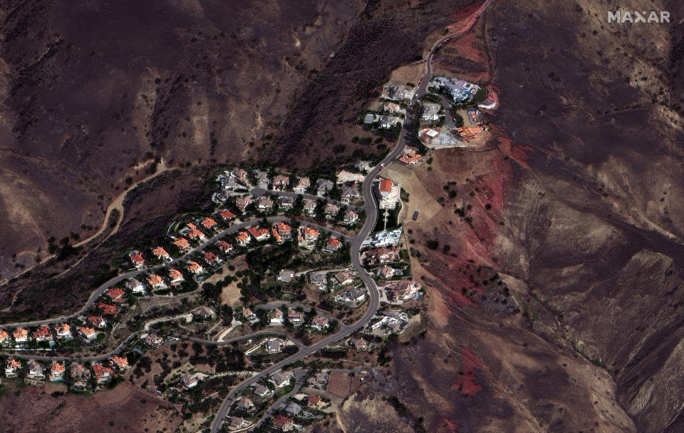 In a photo provided by Maxar Technologies, slurry dropped against the Blue Ridge Fire leaves a red trail to the right of homes in Yorba Linda, Calif., Wednesday, Oct. 28, 2020. Thousands of Californians were allowed to return to their homes Wednesday as calmer winds helped firefighters beat back two wind-driven wildfires that had spurred widespread evacuations. (Maxar Technologies via AP)