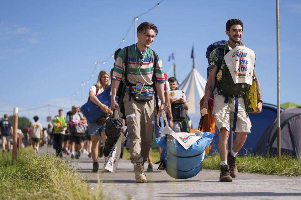 Festival goers walk through the campsite at the Glastonbury Festival in Worthy Farm, Somerset, England, Thursday, June 23, 2022. Thousands of people are returning to England's Glastonbury Festival as the five-day music and performing arts event reopened Wednesday for the first time in three years after being disrupted by the COVID-19 pandemic. (AP Photo/Scott Garfitt)