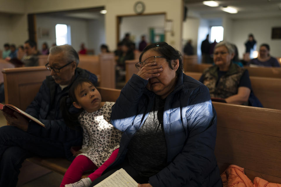 Janet Kiyutelluk, 57, wipes her tears while singing a hymn as her granddaughter, Lacey Barr, 3, watches during a Sunday service at the Shishmaref Lutheran Church in Shishmaref, Alaska, Sunday, Oct. 2, 2022. (AP Photo/Jae C. Hong)