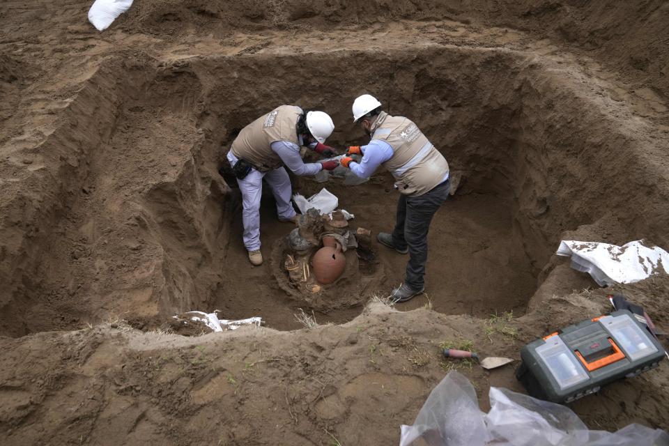 Archaeologists uncover vessels and bones discovered by city workers who were digging a natural gas line for the company Calidda in the district of Carabayllo on the outskirts of Lima, Peru, Friday, Sept. 22, 2023. Eight burial offerings from the pre-Inca Ychsma culture have been identified by archeologists so far, according to lead archeologist Jesus Bahamonde. (AP Photo/Martin Mejia)