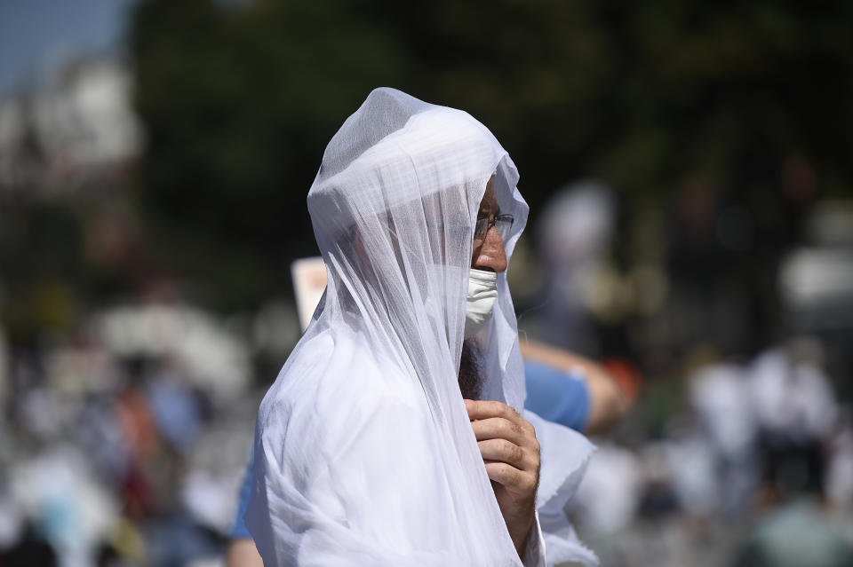 Faithful, wearing masks to avoid the spread of coronavirus, wait at the historic Sultanahmet district of Istanbul, near the Byzantine-era Hagia Sophia, Friday, July 24, 2020. Hundreds of Muslim faithful were making their way to Istanbul's landmark monument Friday to take part in the first prayers in 86 years at the structure that was once Christendom's most significant cathedral and the "jewel" of the Byzantine Empire then a mosque and museum before its re-conversion into a Muslim place of worship. The conversion of the edifice, has led to an international outcry. (AP Photo/Yasin Akgul)