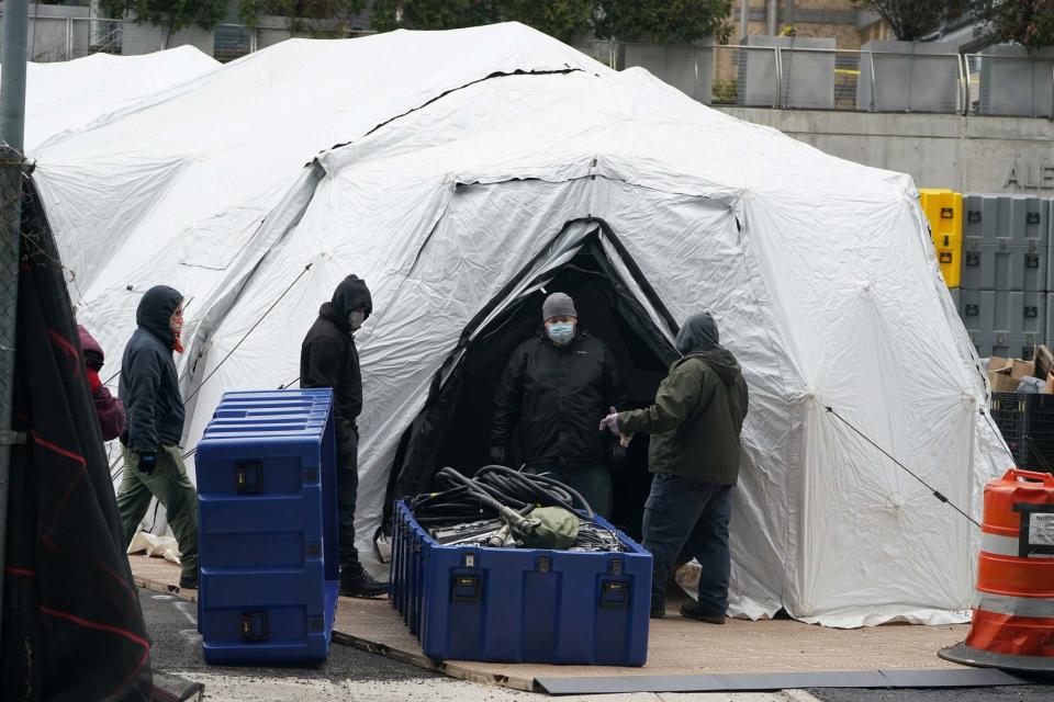 Workers construct what is believed to be a makeshift morgue behind a hospital in New York (REUTERS)