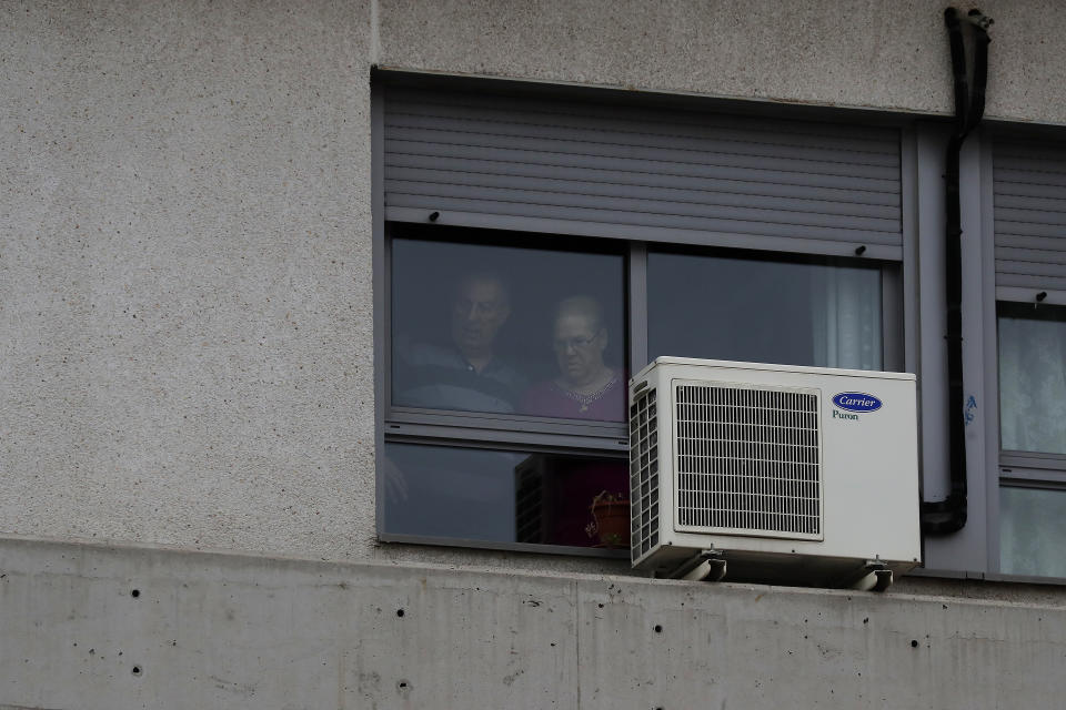 People look out from a window inside of a nursing home where dead bodies were found at the nursing homes of Usera in Madrid, Spain, Tuesday, March 24, 2020. Spanish army troops disinfecting nursing homes have found, to their horror, some residents living in squalor among the infectious bodies of people that authorities suspect have died from the new coronavirus. Prosecutors have launched a judicial probe. For some, it can cause more severe illness, especially in older adults and people with existing health problems. (AP Photo/Manu Fernandez)