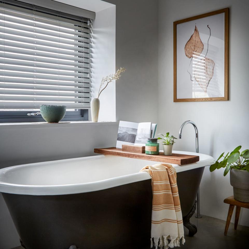 a freestanding bathtub with a rack and towel on the side