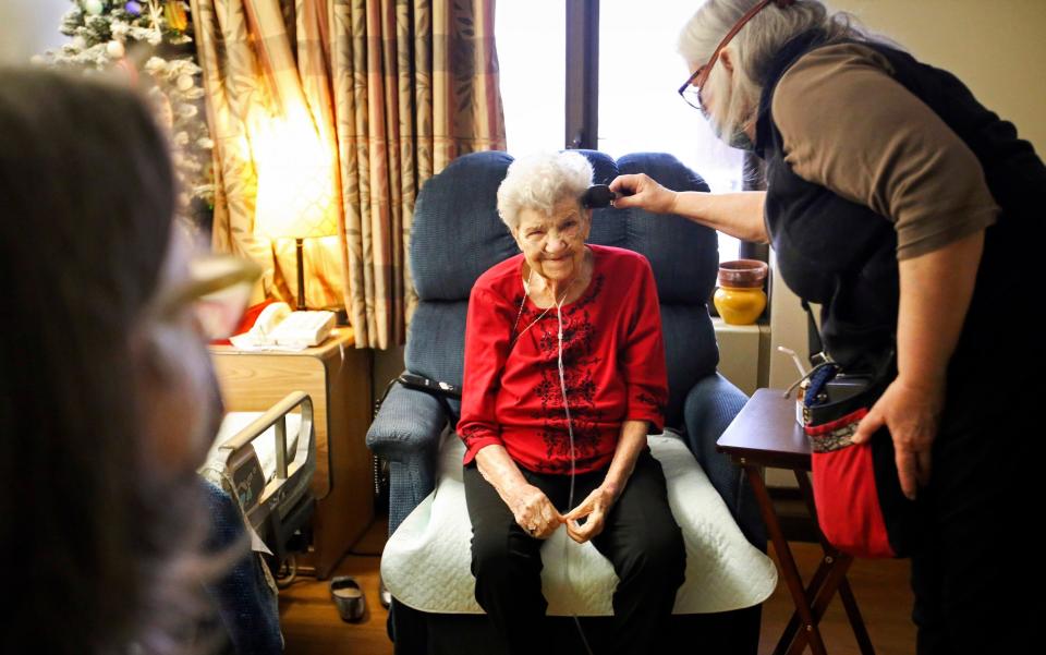 Kim Kiml brushed her mother's hair while she and her sister, Winter Wolf, visited her at the Pioneer Home in Anchorage, Alaska, on Wednesday. Their mother, Ellie Brimanis, hasn't been allowed to have visitors since mid-March of last year due to coronavirus pandemic restrictions - Emily Mesner/Anchorage Daily News via AP