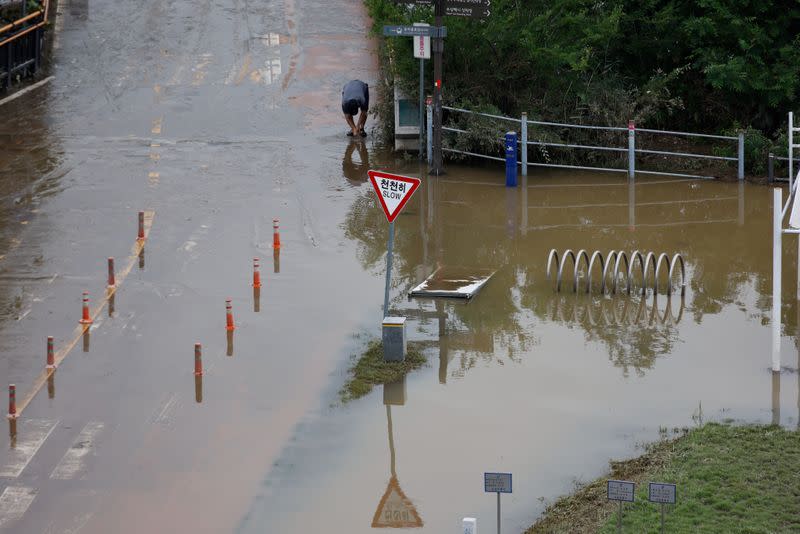 A man washes off mud from his hands at a flooded Han River park in Seoul