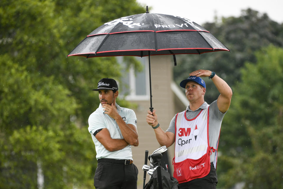 Rafa Cabrera Bello, left, waits with caddie Ben Hulka for play to resume after a rain delay at the 18th hole during the first round of the 3M Open golf tournament in Blaine, Minn., Thursday, July 22, 2021. (AP Photo/Craig Lassig)