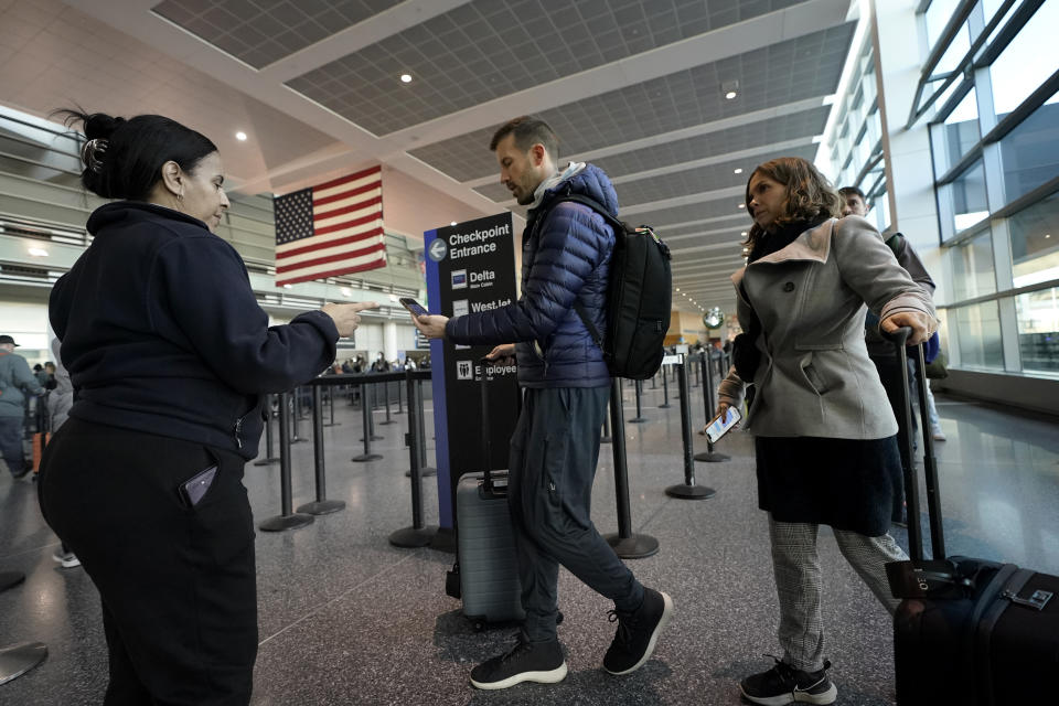 Travelers approach a security checkpoint before boarding their flights the day before Thanksgiving, Wednesday, Nov. 23, 2022, at Logan International Airport in Boston. (AP Photo/Steven Senne)