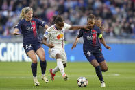 Lyon's Melchie Dumornay runs with the ball between PSG's Korbin Albert, left, and Grace Geyoro during the women's Champions League semifinals, first leg, soccer match between Olympique Lyonnais and Paris Saint-Germain at Parc Olympique Lyonnais, in Lyon, France, Saturday, April 20, 2024. (AP Photo/Laurent Cipriani)