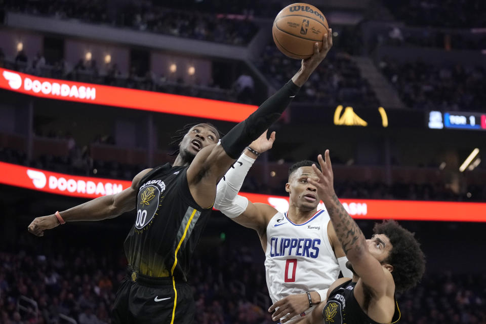 Golden State Warriors forward Jonathan Kuminga, left, grabs a rebound in front of forward Anthony Lamb, bottom, and Los Angeles Clippers guard Russell Westbrook (0) during the first half of an NBA basketball game in San Francisco, Thursday, March 2, 2023. (AP Photo/Jeff Chiu)
