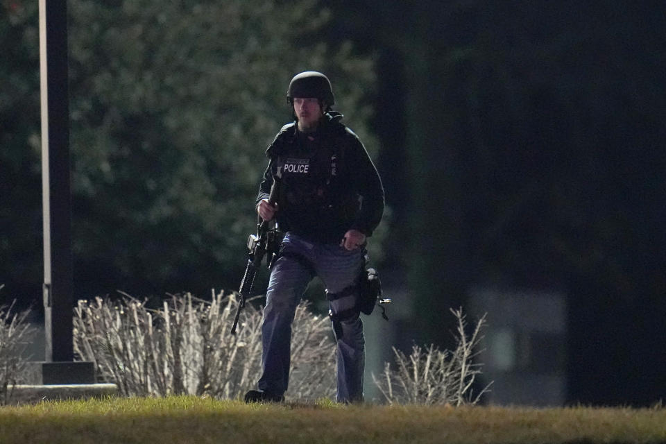 An official walks near a wooded area during a search for a gunman early Friday, Feb. 10, 2023, in Fallston, Md. A suspect sought in the shooting of two Maryland police officers was surrounded by law enforcement after fleeing from the vehicle he had stolen from a detective he shot Thursday night, authorities said. (AP Photo/Julio Cortez)