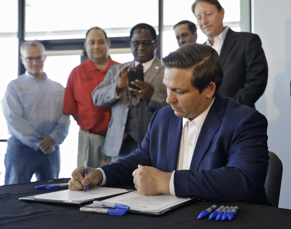 Florida Gov. Ron DeSantis signs a red tide mitigation and technology development initiative into law during a news conference at Mote Marine Laboratory and Aquarium Thursday, June 20, 2019, in Sarasota, Fla. DeSantis says Florida will commit $3 million for the next five years for the purpose of prioritizing red tide prevention. (AP Photo/Chris O'Meara)