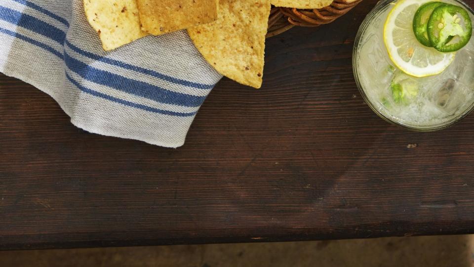 restaurant style salsa in a small white bowl in a basket of tortilla chips