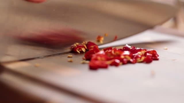 Slicing red chilli padi with a knife