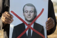 An Israeli Arab protester holds a defaced picture of French President Emmanuel Macron, during a small demonstration protesting published caricatures of the Prophet Muhammad deemed insulting and blasphemous, in Hura, a Bedouin village in the Negev desert, Israel, Monday, Oct. 26, 2020. (AP Photo/Sebastian Scheiner)