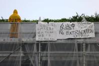 A person stands on a scaffolding surrounding the Pacific Place complex next to a banner related to the protests against the proposed extradition bill, in Hong Kong