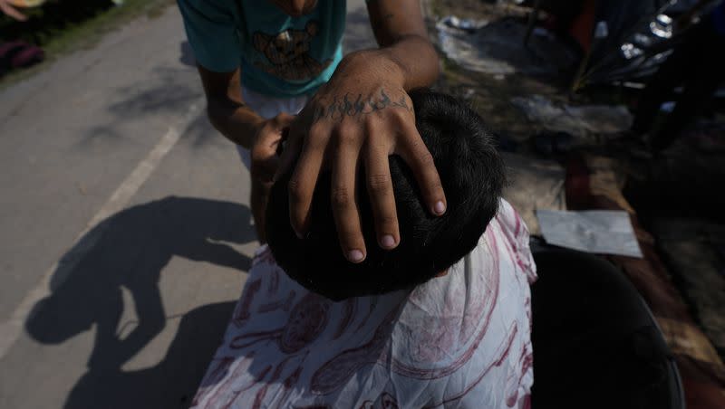 A Venezuelan migrant cuts the hair of another on the banks of the Rio Grande in Matamoros, Mexico, Sunday, May 14, 2023. As the U.S. ended its pandemic-era immigration restrictions, migrants are adapting to new asylum rules and legal pathways meant to discourage illegal crossings.