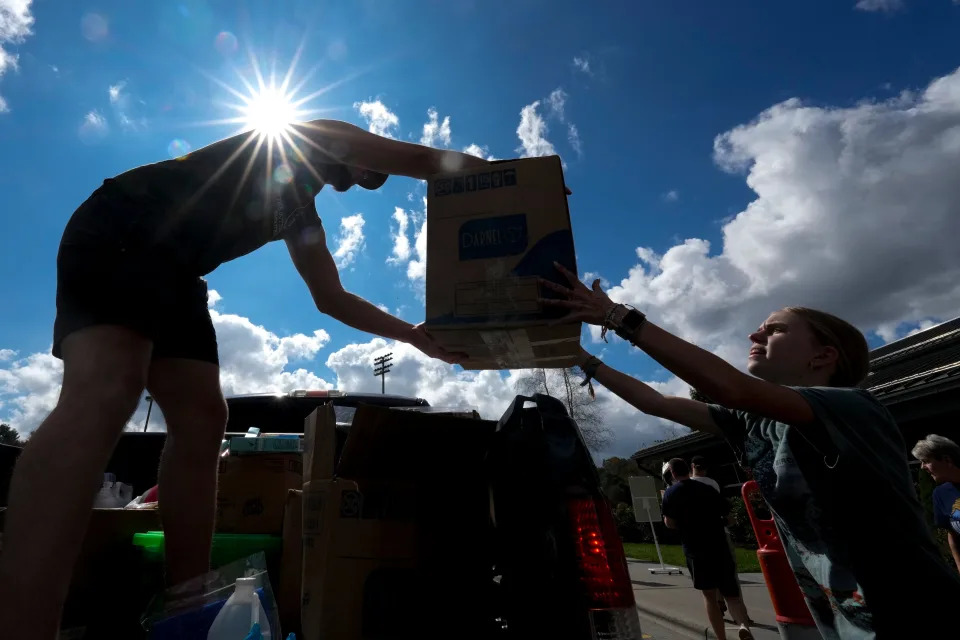 A young man hands supplies down to a woman from the bed of a truck amid hurricane recovery efforts.