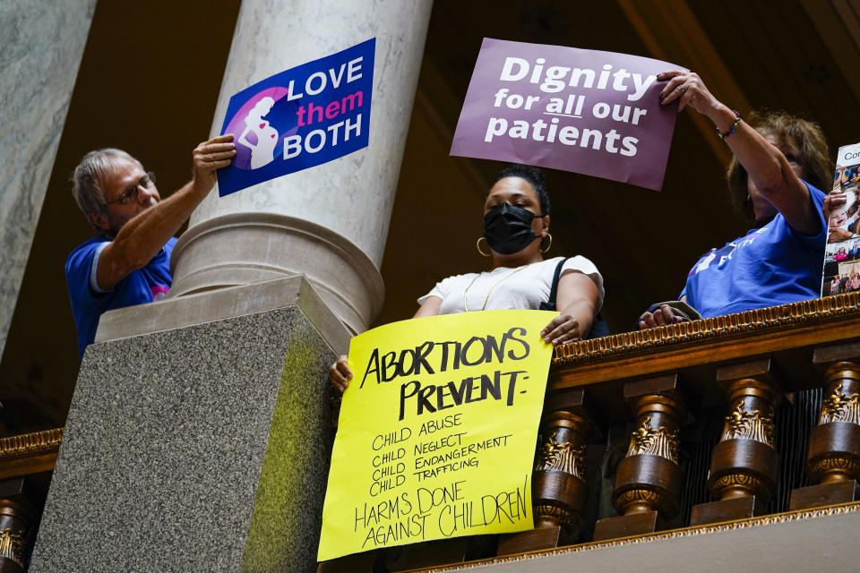 Anti-abortion supporters try to cover a sign of an abortion rights supporter during an anti-abortion rally as the Indiana Senate Rules Committee met a Republican proposal to ban nearly all abortions in the state during a hearing at the Statehouse in Indianapolis, Tuesday, July 26, 2022. (AP Photo/Michael Conroy)