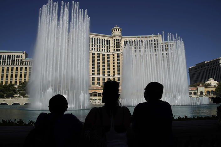 People watch the fountains before the reopening of the Bellagio hotel and casino, Thursday, June 4, 2020, in Las Vegas. Casinos in Nevada were allowed to reopen on Thursday for the first time after temporary closures as a precaution against the coronavirus. (AP Photo/John Locher)