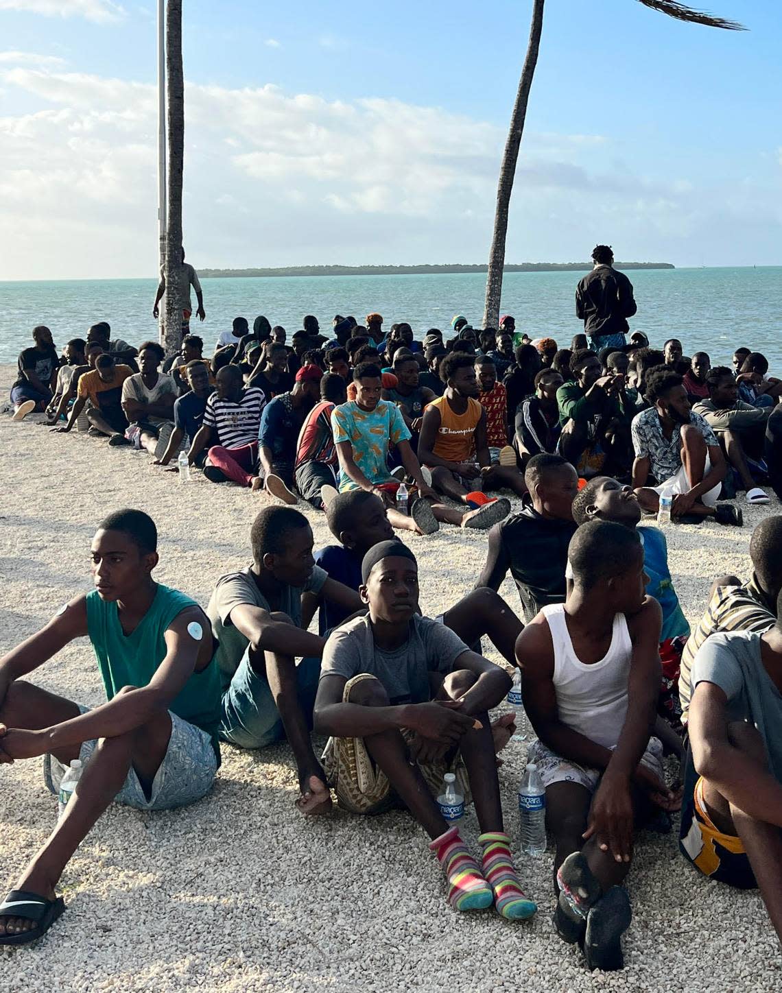 A group of about 100 men from Haiti gather on a beach in the Upper Florida Keys Thursday, Feb. 9, 2023. Authorities say they arrived on an overloaded migrant sailboat.