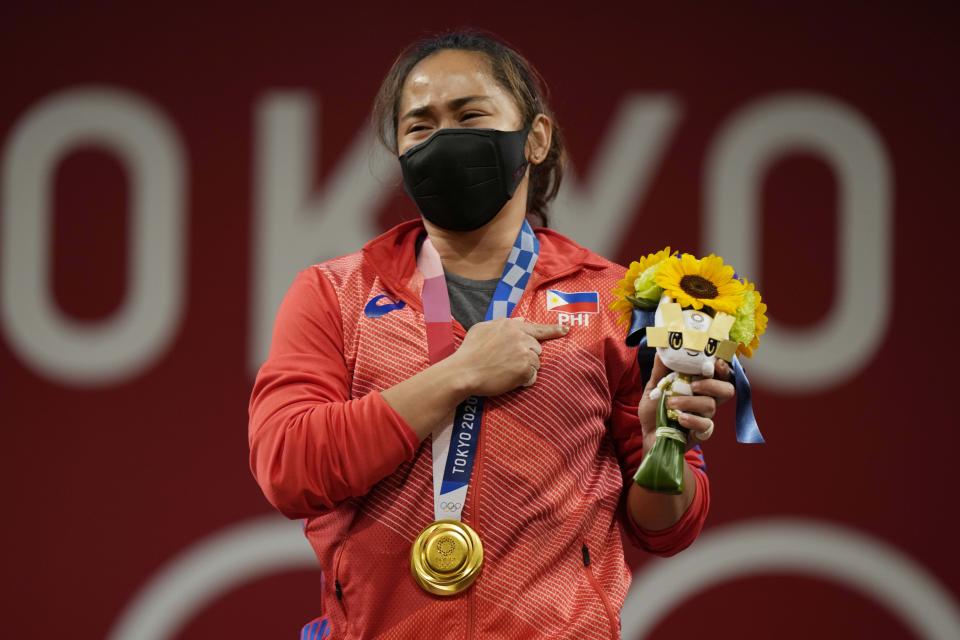 Hidilyn Diaz of Philippines celebrates on the podium after winning the gold medal in the women's 55kg weightlifting event, at the 2020 Summer Olympics, Monday, July 26, 2021, in Tokyo, Japan. (AP Photo/Luca Bruno)