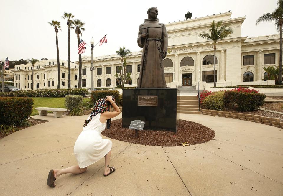A woman photographing Junípero Serra statue