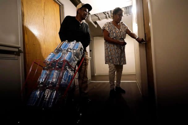 PHOTO: Friends help Golden Keys Senior Living apartments residents to transport cases of water in Jackson, Miss., Sept. 1, 2022. A recent flood worsened Jackson's longstanding water system problems.  (Steve Helber/AP)