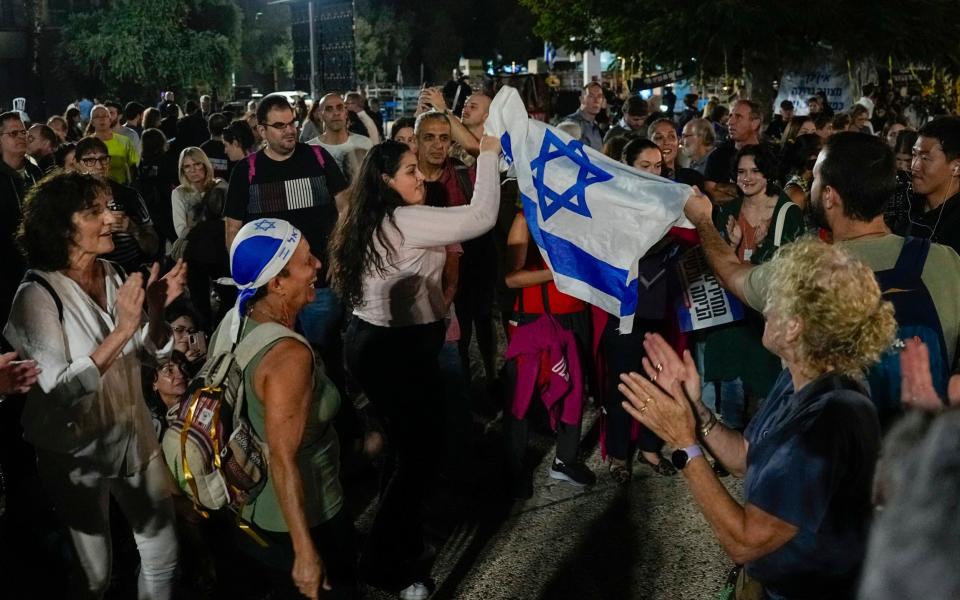 People react as they hear the news of the release of 13 Israeli hostages held by Hamas in the Gaza strip, in Tel Aviv, Israel, on Friday, Nov. 24, 2023. Friday marks the start of a four-day cease-fire in the Israel-Hamas war, during which the Gaza militants pledged to release 50 hostages in exchange for 150 Palestinians imprisoned by Israel. (AP Photo/Ariel Schalit)