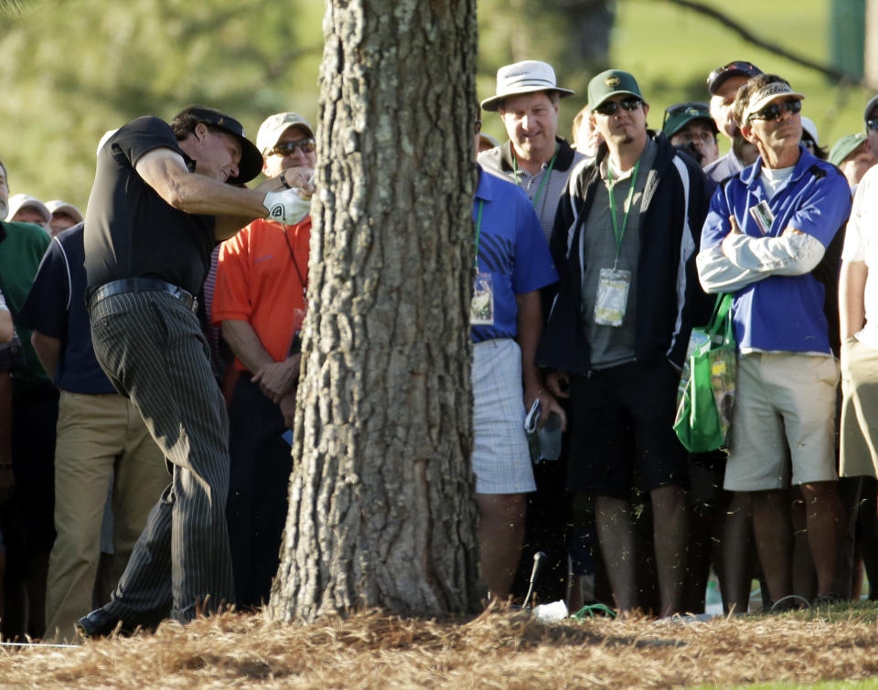 Phil Mickelson hits from behind a tree off the 17th hole during the first round of the Masters golf tournament Thursday, April 10, 2014, in Augusta, Ga. (AP Photo/Charlie Riedel)