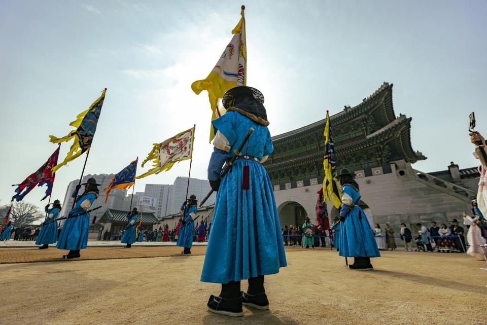 a group of people in blue dresses holding flags