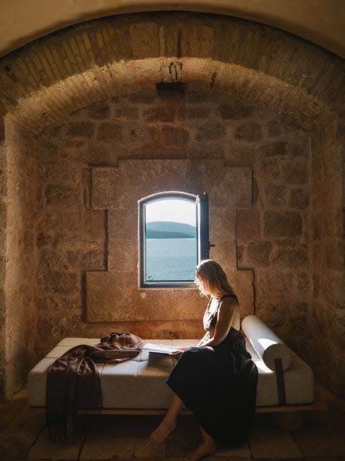 A woman reads by the window inside one of the rooms at the Mamula Island Hotel.