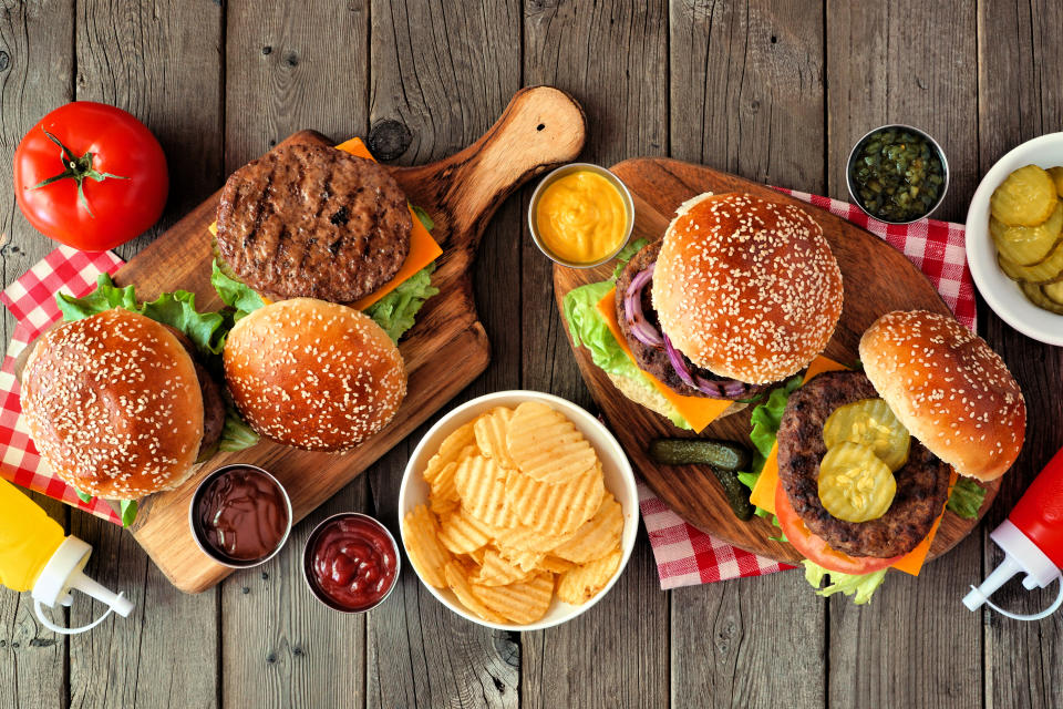 BBQ hamburger table scene. Top view over a dark wood background.