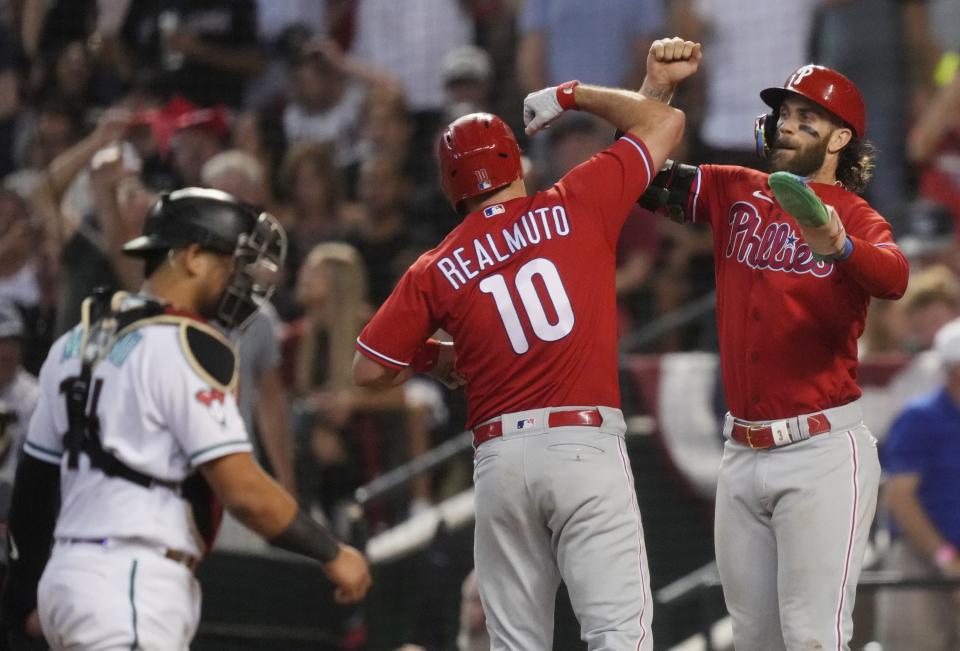 Philadelphia Phillies catcher J.T. Realmuto (10) celebrates with teammate Philadelphia Phillies designated hitter Bryce Harper (3) after hitting a two-run home run as Arizona Diamondbacks catcher Gabriel Moreno (14) looks on in the eighth inning in Game 5 of the NLCS of the 2023 MLB playoffs at Chase Field on Oct. 21, 2023, in Phoenix, AZ. The Phillies beat the Diamondbacks 6-1, giving Philadelphia the overall lead of 3-2 in the NLCS playoffs.