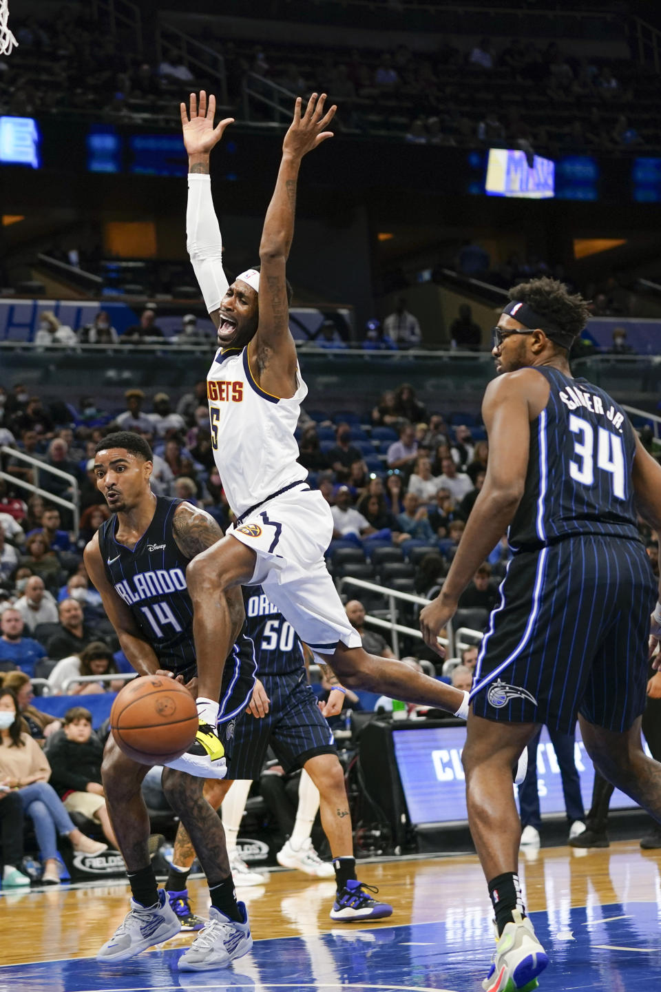 Denver Nuggets forward Will Barton, center, is stripped of the ball as he goes up for a shot between Orlando Magic guard Gary Harris (14) and center Wendell Carter Jr. (34) during the first half of an NBA basketball game, Wednesday, Dec. 1, 2021, in Orlando, Fla. (AP Photo/John Raoux)