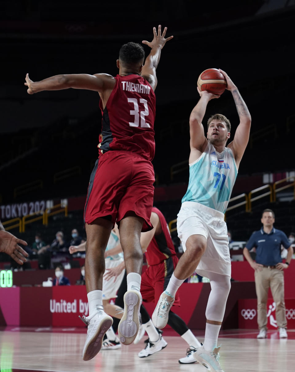 Slovenia's Luka Doncic (77) shoots over Germany's Johannes Thiemann (32) during men's basketball quarterfinal game at the 2020 Summer Olympics, Tuesday, Aug. 3, 2021, in Saitama, Japan. (AP Photo/Charlie Neibergall)